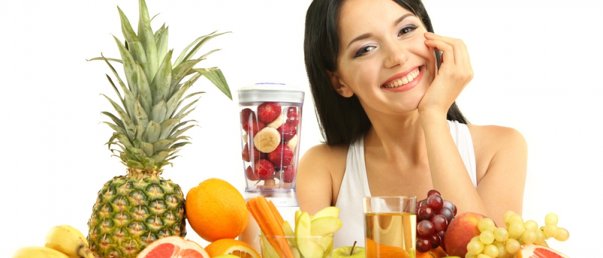 Eine Frau sitzt vor Obst und will Vitamine für Kosmetik