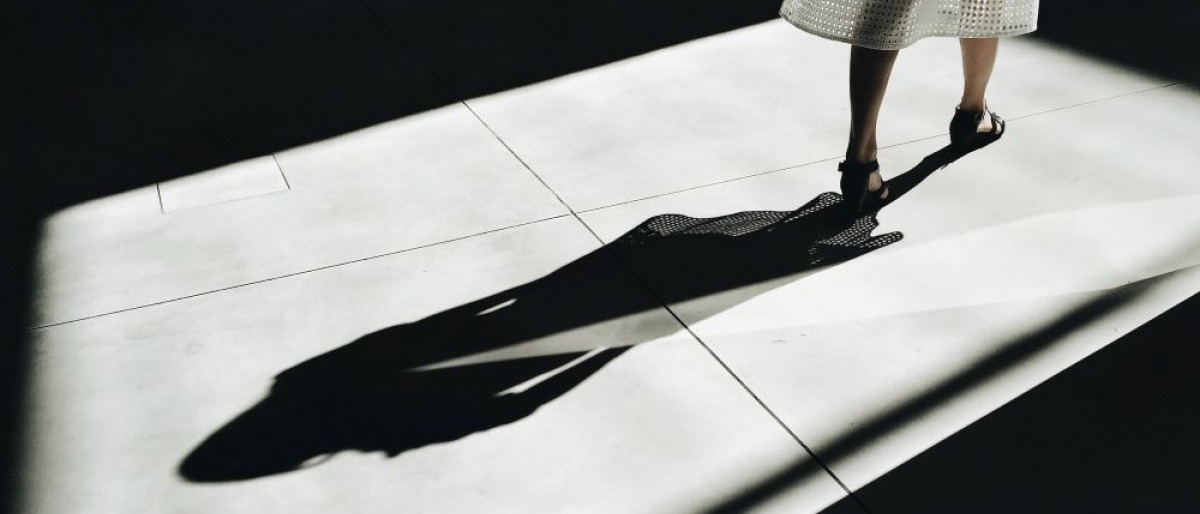 Eine Frau geht vor ihrem Schatten weg