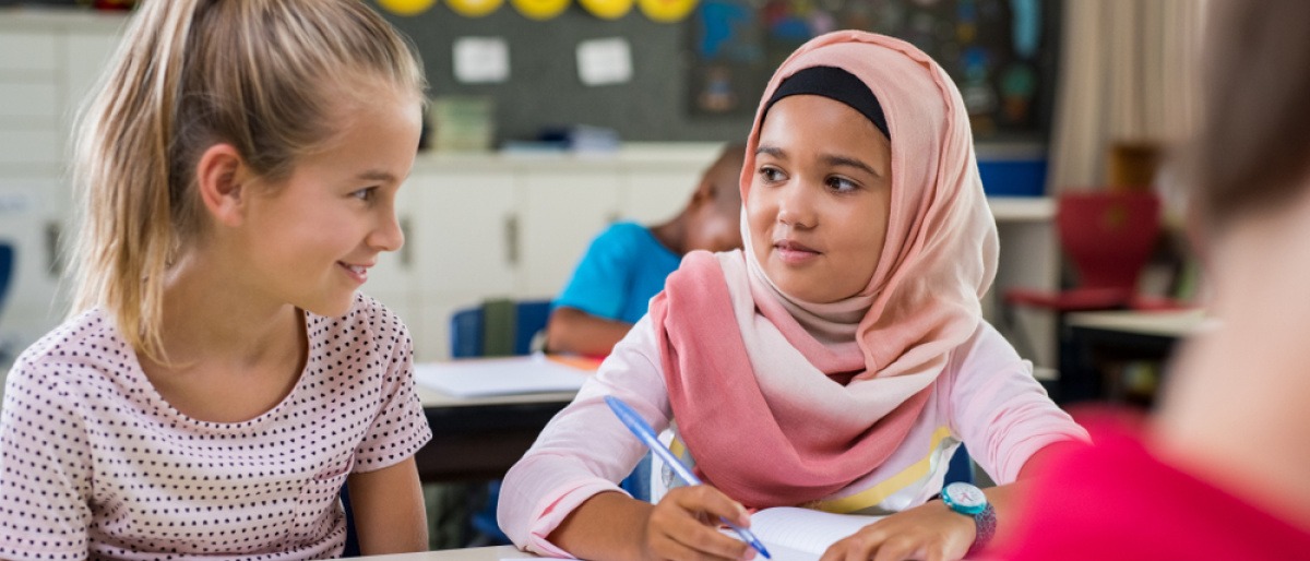 Kinder können am leichtesten Vorurteile abbauen, wie man am Beispiel dieses jungen arabischen Mädchens mit Hidschab bei einer Übung mit ihrer besten Freundin in der Schule sieht.