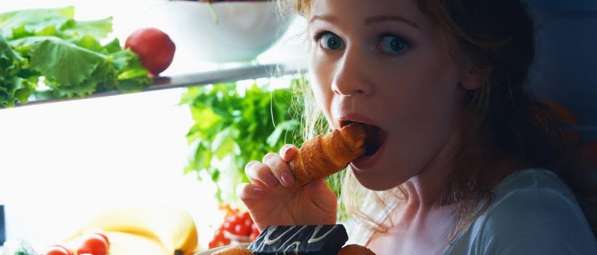 Die Frau, die in diesem Bild vor dem Kühlschrank kniet und ungesunde Snacks isst, hat die Antwort auf die Frage "was soll ich kochen?" für sich selbst bereits beantwortet. Doch gesund essen geht auch mit wenig Zeitaufwand. 