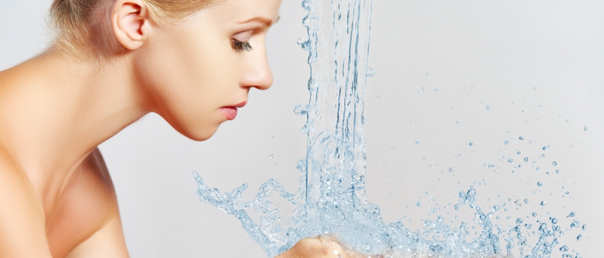 Eine Frau will sich das Gesicht mit Wasser waschen