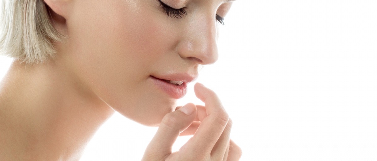 Eine Frau trägt Lippenbalsam mit dem Finger auf.