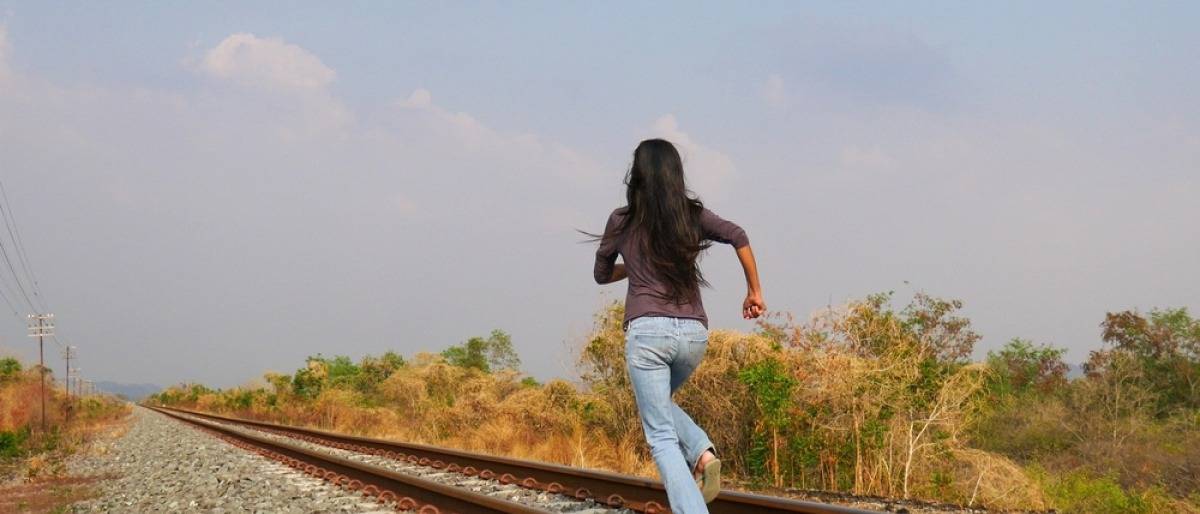 Eine Frau will auf Bahngleisen vor Problemen weglaufen.