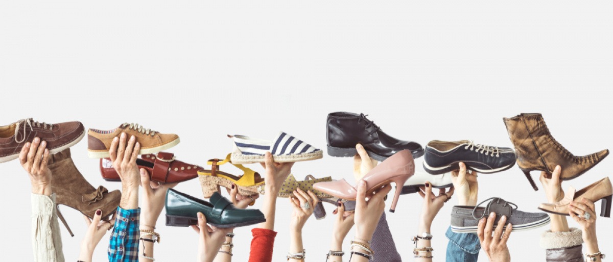 Hände halten viele Schuhe