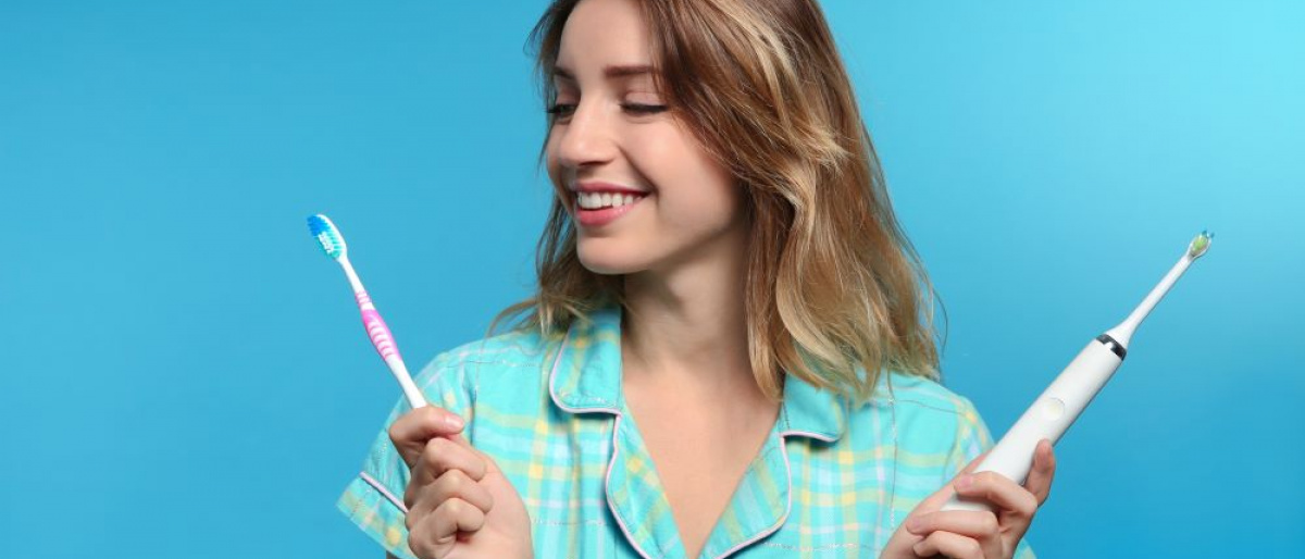 Frau mit schönen Zähnen hält zwei verschiedene Zahnbürsten