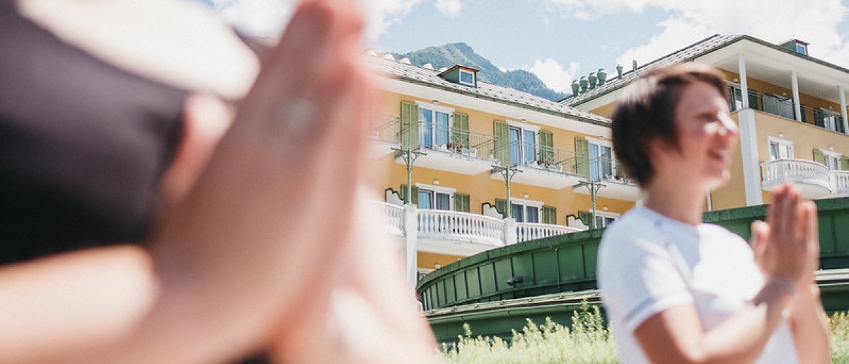 Zwei Frauen machen Yoga vor dem Alpenhaus Gasteinertal