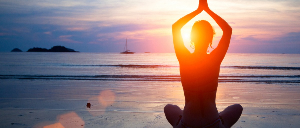 Jemand macht Yoga im Urlaub am Strand