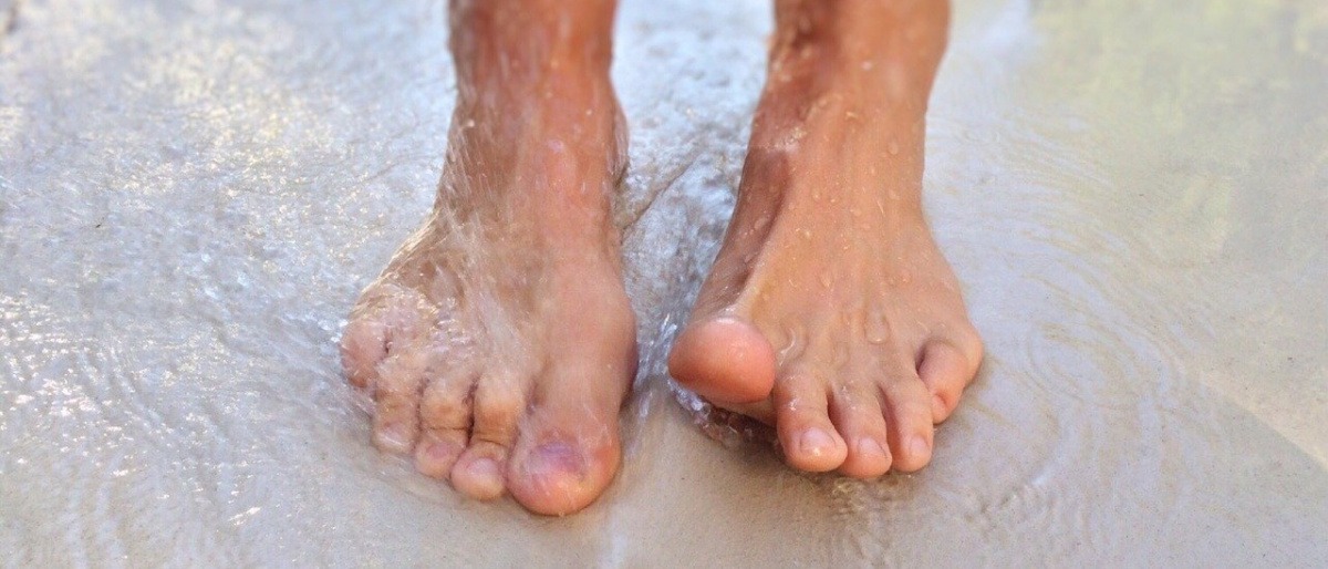Füße im Wasser mit Zehen ohne Nagelpilz
