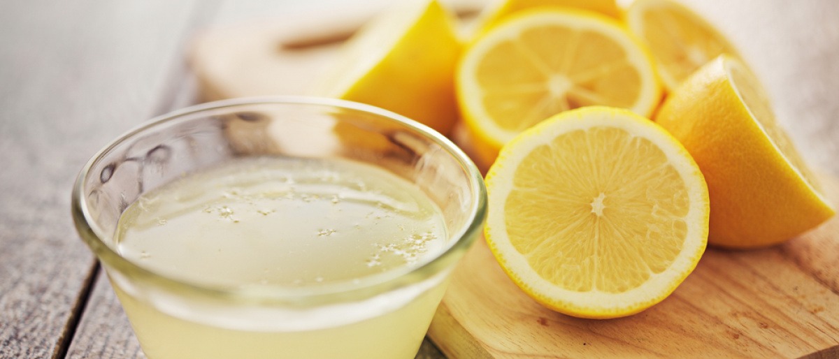 Zitronen liegen neben einer Schüssel Zitronensaft gegen Pickel