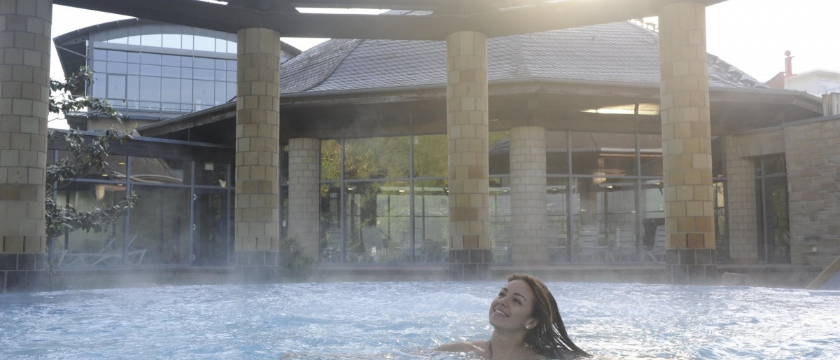 Eine Frau schwimmt im Thermenbereich des Parkhotel Kurhaus