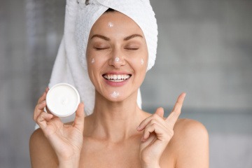 Frau trägt eine Anti-Aging Nachtcreme auf und lächelt