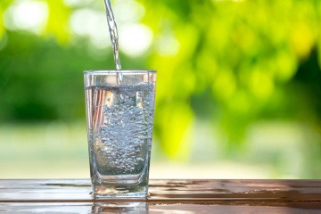 Leitungswasser oder Mineralwasser wird in ein Glas geleert