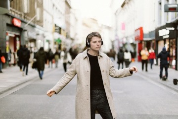 Junger Mann mit Kopfhörern tanzt in Freiheit auf der Straße einer Stadt