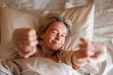 Frau streckt sich gut erholt im Bett