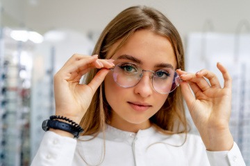 Frau setzt runde Brille als Brillentrend 2023 auf