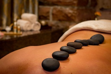 Auf einem Rücken liegen Steine für eine Hot Stone Massage