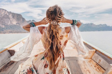Frau im Sommerkleid fährt mit Boot über See.