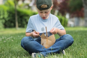 Junge bekommt beim Essen Fettflecken in die Jeans