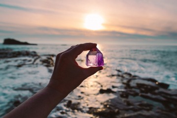 Frau hält Amethyst in den Sonnenuntergang.