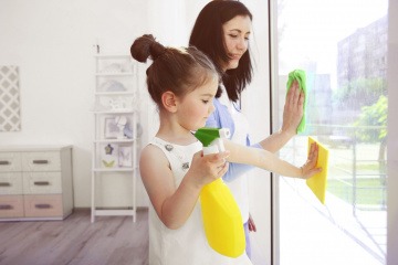Frau und Mädchen putzen ein Fenster mit selber gemachtem Glasreiniger