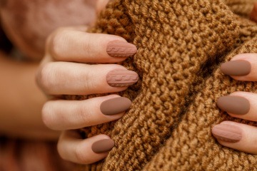 Finger mit Nagellack in Nagellack-Trend braun