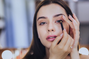 Frau schminkt sich die Augen mit Kajal