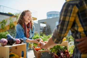 Frau kauft am Markt regionales Gemüse als Ernährungstrend 2024