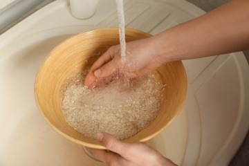Frau wäscht Reis in einer Schüssel