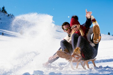 Mann und Frau beim Rodeln, einer Sportart im Winter