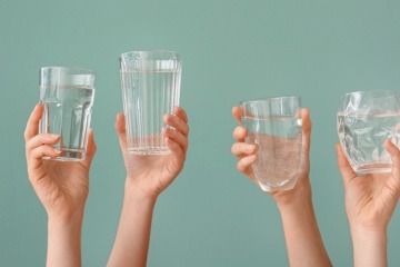 Hände halten Gläser mit Trinkwasser in die Luft