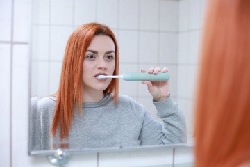 Frau putzt mit einer elektrischen Zahnbürste