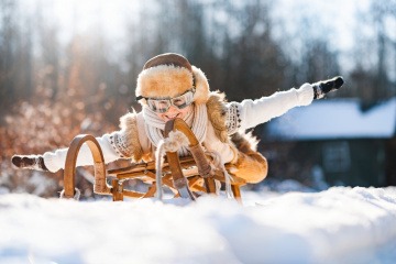 Person auf einer Rodel gegen Winterblues