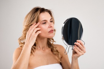 Frau ohne Akne sieht sich in den Spiegel