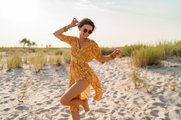 Glückliche Frau geht kraftvoll im Sand spazieren