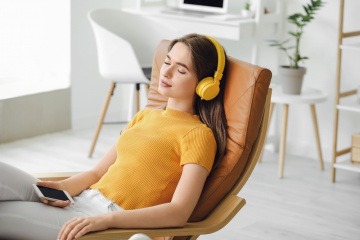 Frau mit Kopfhörern am Liegestuhl bei einer Auszeit