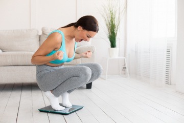 Frau auf der Waage ärgert sich über ihr Zunehmen durch Stress