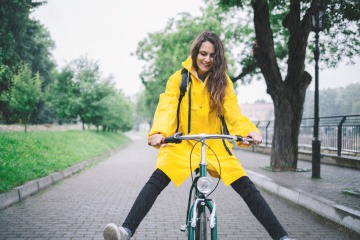 Eine Frau mit Regenhose und Regenjacke fährt mit dem Fahrrad