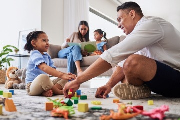 Mann und kleines Mädchen spielen als Familienaktivität mit Bausteinen