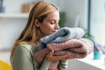 Frau riecht an einem Stapel Handtücher