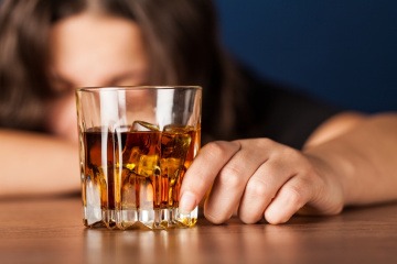 Ein Glas Alkohol vor einer Alkoholikerin 