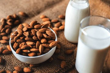 Nüsse liegen neben einem Glas Milch. Beide enthalten Aminosäuren