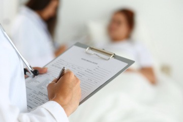 Ein Arzt schreibt eine Diagnose auf ein Datenblatt