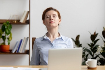 Frau im Büro macht Atemübungen gegen Stress