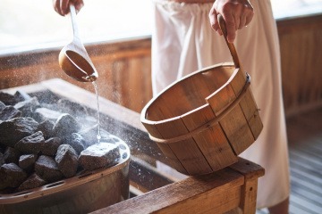 Ein Mann macht einen Aufguss in der Sauna mit ätherischen Ölen