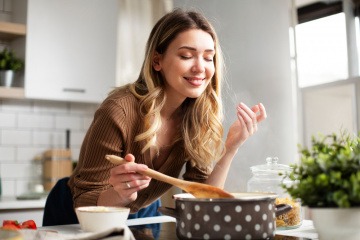 Frau beim Kochen genießt Duft der Speisen