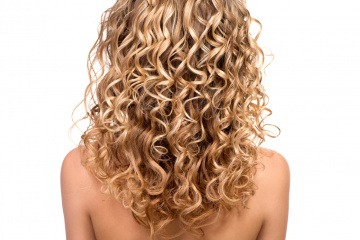Eine Frau mit Haaren in der Strähnchentechnik Balayage oder Foliyage ist von hinten zu sehen