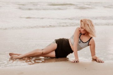 Eine Frau liegt am Strand, ihre Oberschenkel sind ohne sichtbare Cellulite