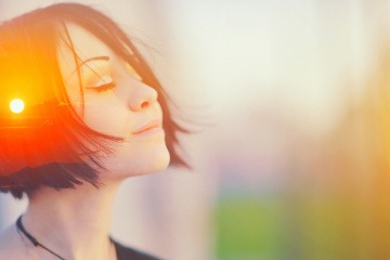 Eine Frau sieht bewusst aus, in ihrem Kopf leuchtet die Sonne
