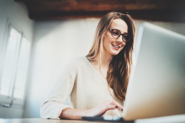 Eine Frau hat bei der Bildschirmarbeit eine Brille auf