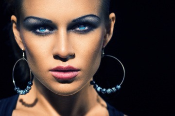 Eine Frau hat mit blauem Lidschatten Smokey Eyes geschminkt
